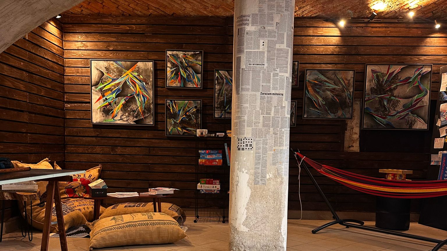 Wnętrze Art Loop: obrazy na drewnianych ścianach, hamak, pufy z worków po kawie